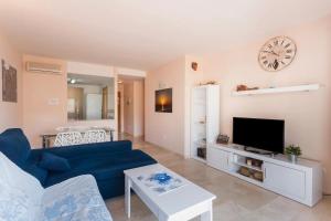 a living room with a blue couch and a clock on the wall at Apartamento EntreOlas in El Verger