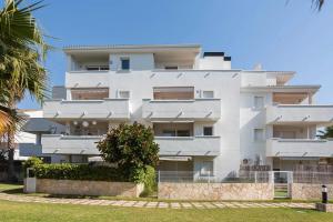 a white building with a palm tree in front of it at Apartamento EntreOlas in El Verger