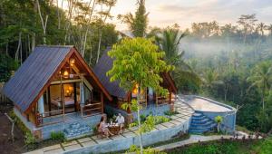 a house in the forest with people sitting in front of it at The Grembeng in Undisan