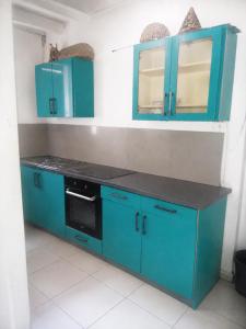 a kitchen with blue cabinets and a black counter top at Papaya Camping in Les Abymes