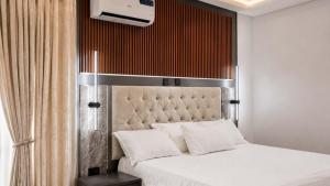a bedroom with a white bed with a large headboard at Richgates Apartments in Enugu