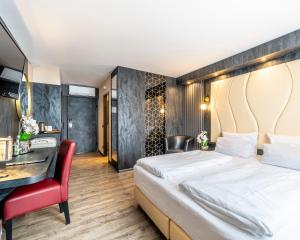 a hotel room with a bed and a desk at PLAZA INN Bruchsal in Bruchsal