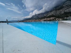a pool of blue water with a city in the background at Amfora-modern apartments with pool in Makarska