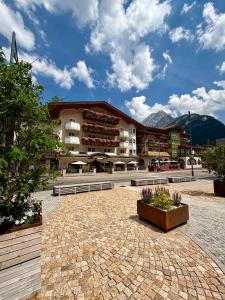 ein großes Gebäude mit einem davorliegenden Innenhof in der Unterkunft Hotel Alba Wellness & Spa in Canazei