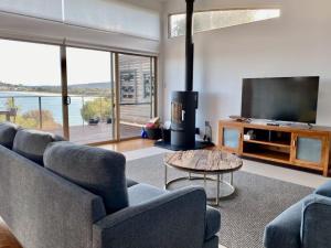 a living room with couches and a flat screen tv at Waterfront Primrose Retreat in Primrose Sands