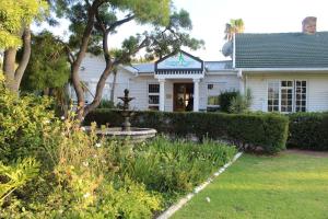 a white house with a fountain in the yard at Somer Place B&B in Somerset West
