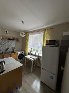 a kitchen with a white refrigerator and a table at Sunset Stay in Kolka in Kolka