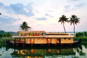 a house boat on the water with palm trees at Boats N Beds - Alleppey Houseboats - Alleppey Boat House - Luxury Premium Houseboats in Alleppey