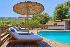 a patio with chairs and an umbrella next to a pool at Villa Galateia in Dhafnés