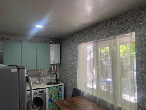 a kitchen with a refrigerator and a table and a window at Weekend House in Borjomi