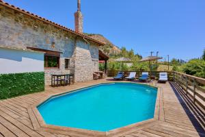 an outdoor swimming pool with a deck and a house at Villa Galateia in Dhafnés