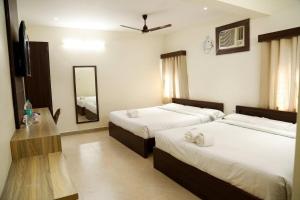 a hotel room with two beds and a mirror at Jazz Inn in Tiruvallūr