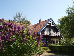 una casa con flores púrpuras delante de ella en Aika, en Nida