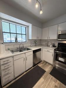 a kitchen with white cabinets and a sink and a window at Cute 1bdr that sleep 4 minutes from ATT Stadium in Arlington