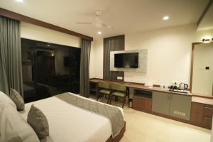 a hotel room with a bed and a desk and a television at Mihas Hotels and Resorts in Malappuram +7 photos