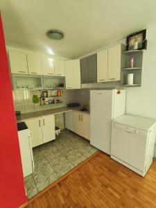 a kitchen with white cabinets and a white refrigerator at Stan Foca N in Foča