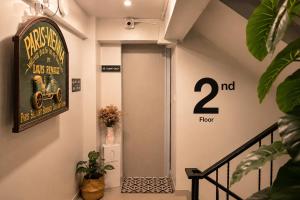 a hallway with a door with a sign and plants at 101 SEOUL HOSTEL (101 โซล โฮสเทล) in Bangkok