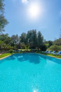 a large blue swimming pool with the sun overhead at Finca Son Xona in Capdepera