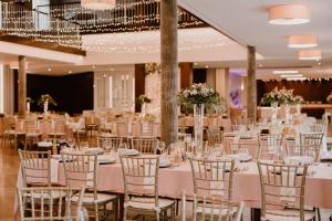 ein Festsaal mit weißen Tischen und Stühlen in der Unterkunft Hotel Arkas in Proskau
