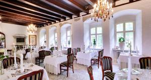 a restaurant with white tables and chairs and a chandelier at Kokkedal Slotshotel in Brovst