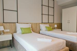 two beds in a hotel room with green pillows at Hotel Hills in Donji Štoj
