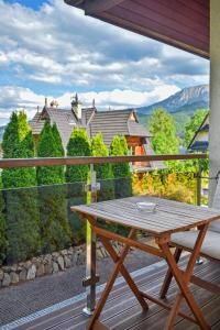 a wooden table on a balcony with a view of a house at Apartamenty Widokowe Pod Lasem in Kościelisko