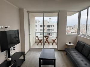 a living room with a couch and a large window at Moderno departamento cercano a playa in La Serena +13 photos