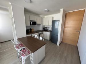 a kitchen with a counter and chairs in a room at Moderno departamento cercano a playa in La Serena