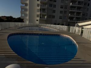 a large blue swimming pool next to a white fence at Moderno departamento cercano a playa in La Serena