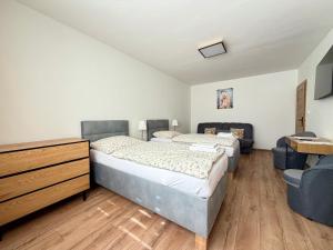 a bedroom with two beds and a dresser and chairs at Apartmánový byt Flower in Kadaň