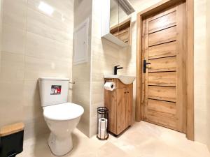 a bathroom with a toilet and a wooden door at Apartmánový byt Flower in Kadaň +2 photos