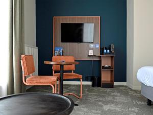 a room with two chairs and a table and a tv at Fletcher Hotel Paleis Stadhouderlijk Hof in Leeuwarden