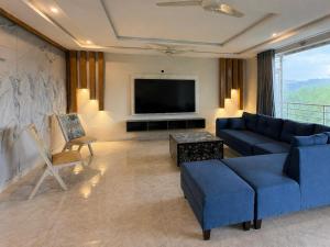 a living room with a blue couch and a television at The Elysian Villa in Bhurban