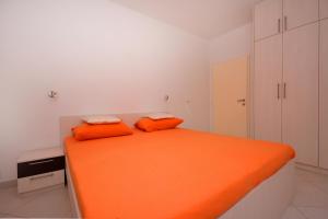 uma cama laranja com duas almofadas laranja num quarto em Apartman Suzana em Omiš