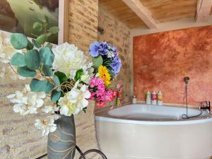 a vase filled with flowers next to a bath tub at Le Soleilho in Figeac +81 photos