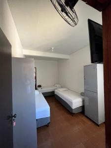 a small room with two beds and a tv at BG Hospedagens in Paracatu