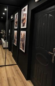 a hallway with black doors and pictures on the walls at Kawalerka in Malbork