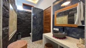 a bathroom with a sink and a stone wall at ABG Villas - Agrowisata Amed in Amed