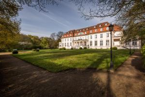 a large white building with a large grass yard at Hotel Schloss Storkau in Storkau