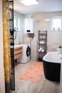 a bathroom with a tub and a washing machine at Apartman NOA in Novska +57 photos