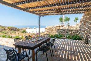 a wooden table and chairs on a patio with the ocean at Aegean Whispers in Agios Fokas