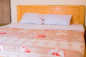 a bed with a wooden headboard and a white pillow at Mariebu Beach Resort in Buhongo
