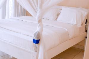 a bed with white sheets and a blue cup on it at Mariebu Beach Resort in Buhongo