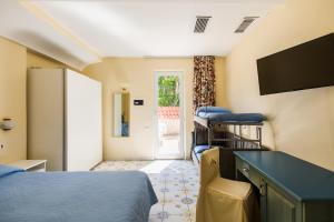 a room with two beds and a desk and a tv at Hotel L'Approdo in Casamicciola Terme