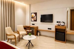 a hotel room with a television and a table and chairs at LUXURIA INN By CHANDAN in Junagadh