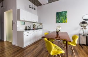 a kitchen with a wooden table and yellow chairs at Gold and Silver Apartment - Manu SPA Lofts in Łódź