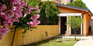 a house with a yellow wall with chairs and pink flowers at La Casetta con giardino privato vicino Cascata delle Marmore in Terni +19 photos