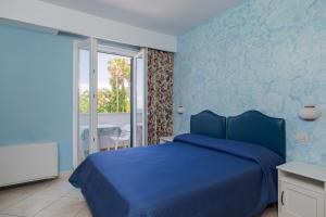 a blue bedroom with a bed and a balcony at Hotel L'Approdo in Casamicciola Terme +89 photos