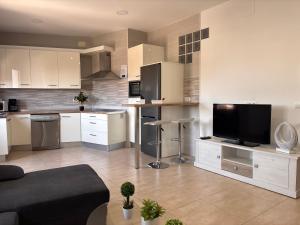a kitchen with white cabinets and a flat screen tv at El rincón de San Bartolomé in Jerez de los Caballeros +27 photos