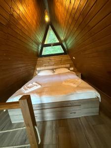 a bed in a wooden room with a window at A-Frame The Wolf Transfăgărășan in Căpăţîneni-Ungureni